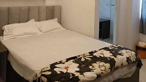 A modern bedroom with a bed, a ceiling fan, and a door leading to another room. - Arnnapurna Hotels & Resorts (Jajapur)