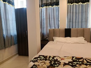 A bedroom with a bed, curtains, and a wardrobe. - Arnnapurna Hotels & Resorts (Jajapur)