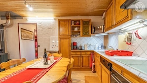 Une cuisine chaleureuse avec des meubles en bois, une table à manger agrémentée de sets de table rouges et un crédence carrelée.