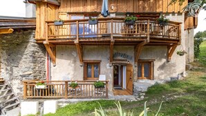 Un chalet rustique doté d’un balcon en bois, de murs en pierre et d’une porte portant l’inscription « La Lombarda ».