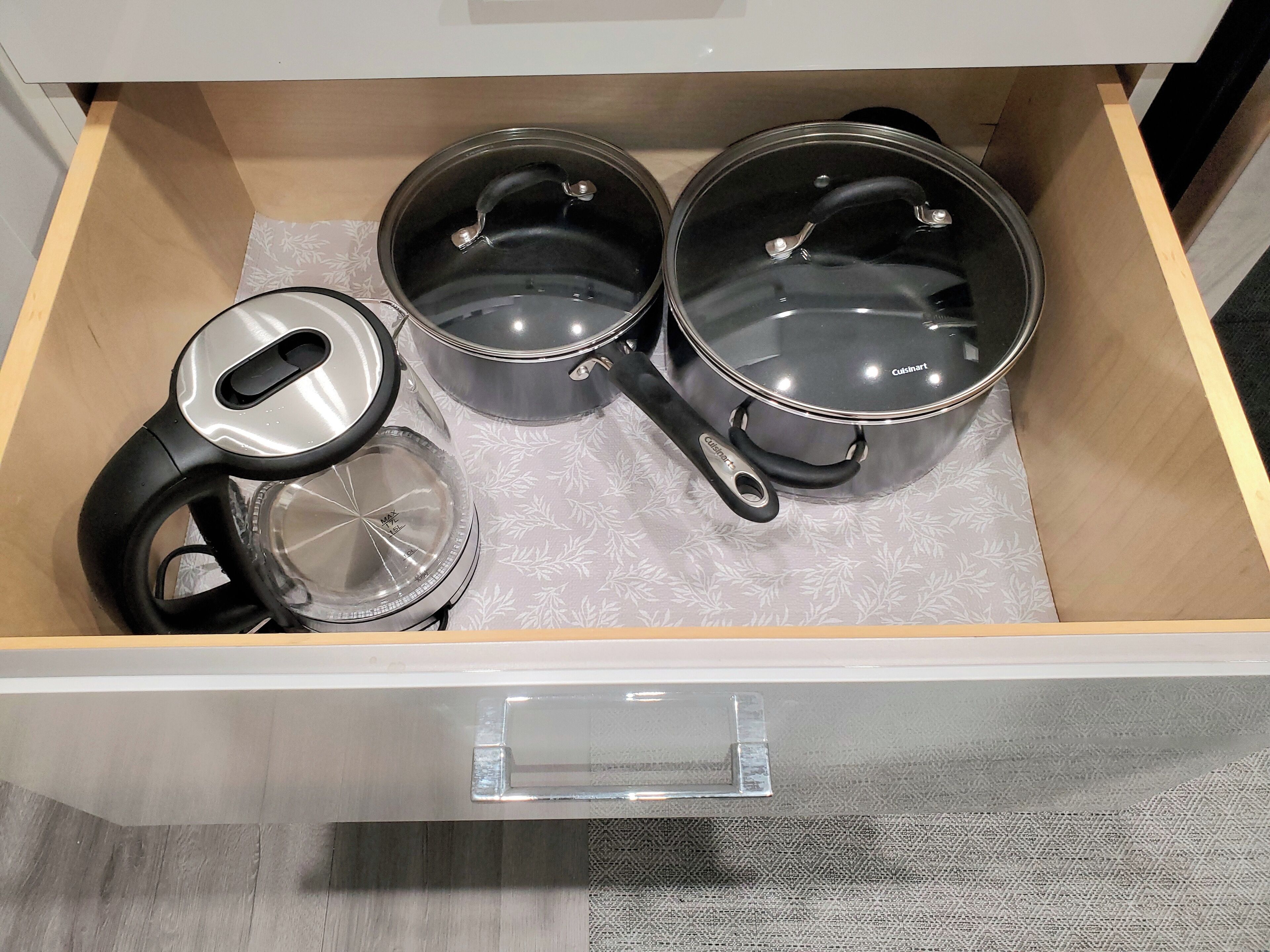 Un tiroir de cuisine contenant trois casseroles et une bouilloire.