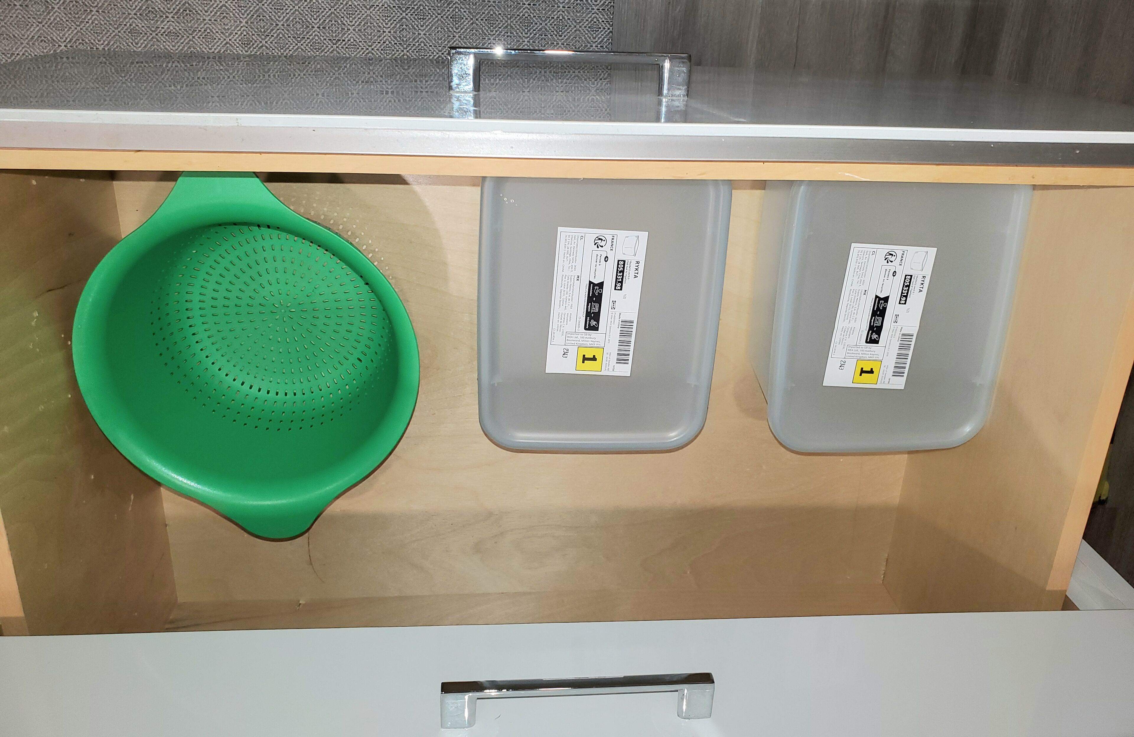 En låda med ett grönt durkslag och två grå plastbehållare.