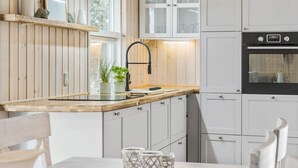 Una cocina moderna con armarios de madera, un grifo negro y un horno empotrado.