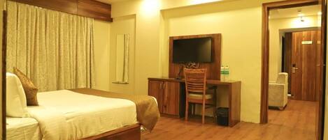 A hotel room with a bed, a desk, a chair, a television, and a wardrobe.