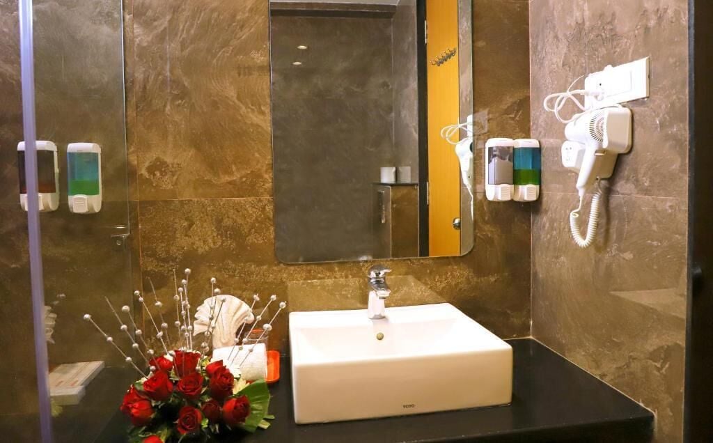 A bathroom with a white sink, a mirror, and a hairdryer on the wall.