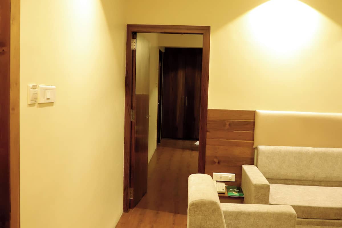 A hallway with wooden flooring, a sofa set, and a wooden door.
