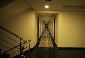 Um corredor comprido e estreito com carpete estampado e corrimão à esquerda.
