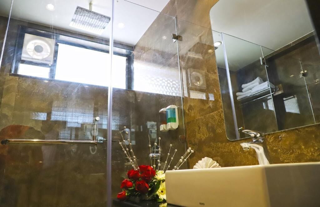 A modern bathroom with a glass shower enclosure, a white sink, and a large mirror.