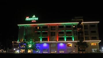A hotel with a sign reading "neemtree HOTEL" and illuminated exterior lighting.