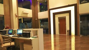 Un espace d’accueil avec un bureau, des ordinateurs et une chaise. On aperçoit une porte au fond.
