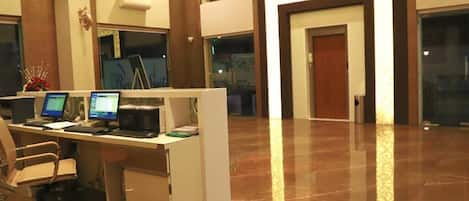 A reception area with a desk, computers, and a chair. There is a door in the background.