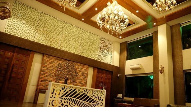 Un hall d’entrée avec un mur orné de motifs géométriques, un comptoir d’accueil et un lustre.