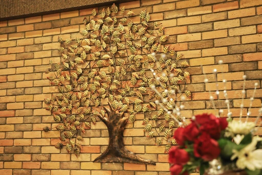Un muro de ladrillo con un árbol decorativo hecho de hojas.