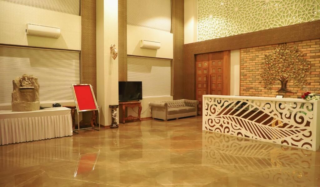 A spacious lobby with a reception desk, a television, and a decorative tree on the wall.