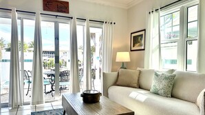 A living room with a sofa, a coffee table, and a view of the outside. - Seas the Keys Getaway with plunge pool/spa (Marathon)