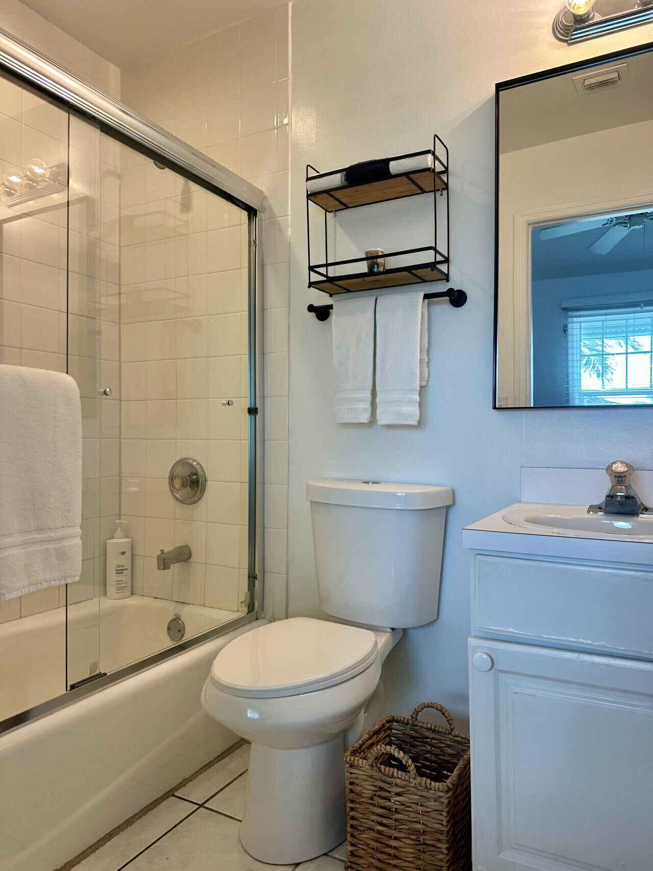 Une salle de bain avec une douche à parois de verre, des toilettes, un lavabo et un miroir.