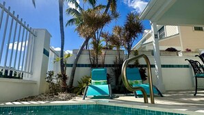 A swimming pool with clear blue water, surrounded by palm trees and lounge chairs. - Seas the Keys Getaway with plunge pool/spa (Marathon)