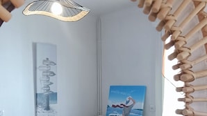 A room with a circular wooden frame structure, a colorful striped sofa, a radiator, and a wall with two artworks. - Rosemonde  Terrasse, calme  esprit village à La Chaume (Les Sables-d´Olonne)