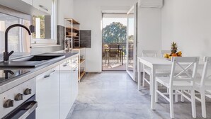 Una cocina moderna con armarios blancos, horno integrado y un amplio ventanal.