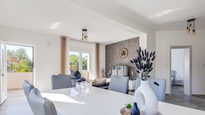 Un comedor moderno con una mesa blanca, sillas grises y un jarrón con plantas.