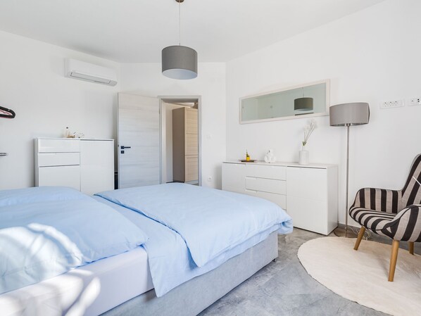 Une chambre à coucher moderne avec un lit, une commode, une chaise et un miroir.