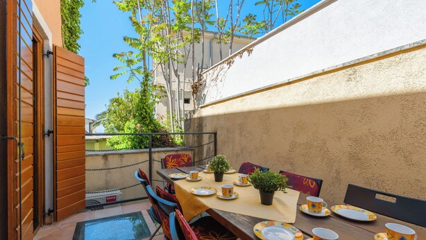 An outdoor patio with a table set for dining, chairs, and a potted plant. - Vista 2 by Interhome (Vrsar)