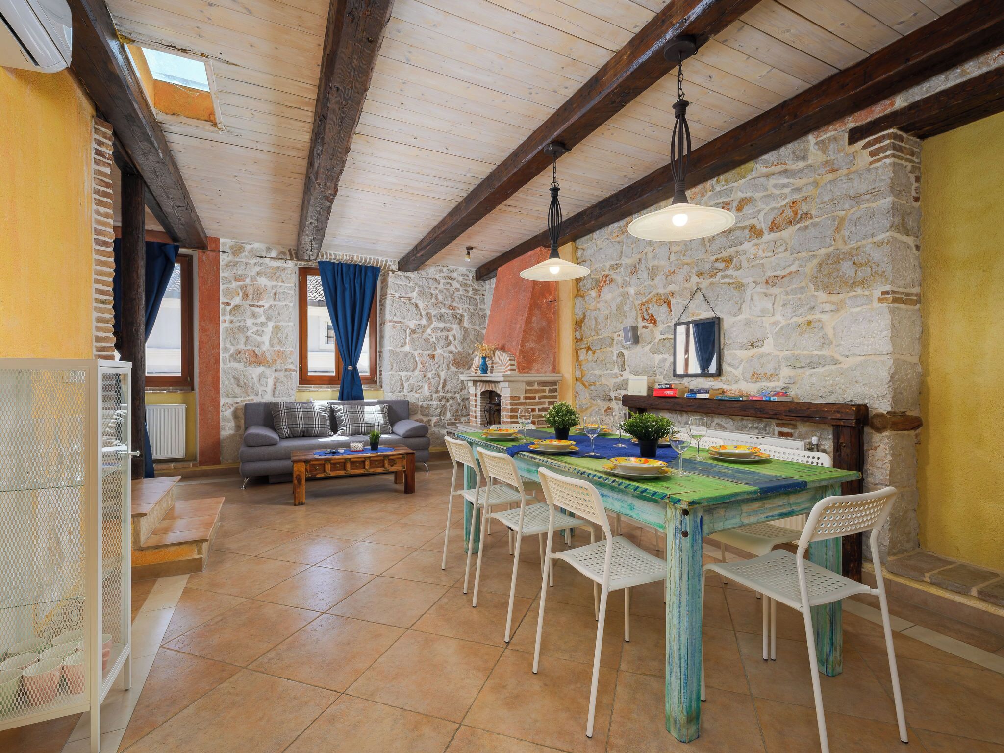 A rustic dining area with a stone wall, wooden beams, and a table set for four.