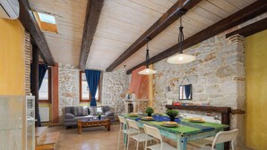 A rustic dining area with a stone wall, wooden beams, and a table set for four. - Vista 2 by Interhome (Vrsar)