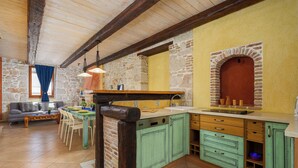 A rustic kitchen with stone walls, wooden beams, and a built-in oven. - Vista 2 by Interhome (Vrsar)