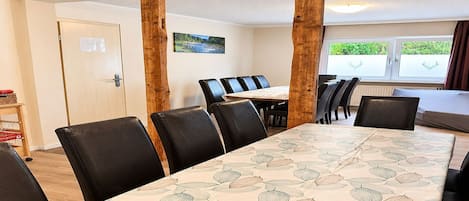 A dining area with a long table, black chairs, and wooden pillars.