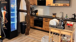 Une cuisine compacte avec des meubles en bois, un réfrigérateur noir et un petit coin repas équipé d’une chaise.