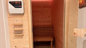 Un sauna en bois, comprenant un banc, un panneau de commande et une porte en bois.