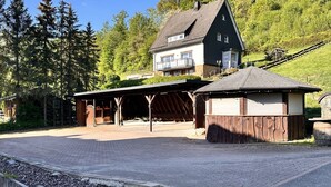 Et toetagers hus med en overdækket veranda og en lille træbygning.
