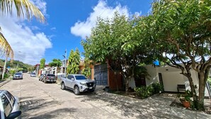 Una strada residenziale con auto parcheggiate, case e alberi.