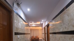 Un pasillo con paredes de mármol, una puerta de madera y una zona de estar con cojines.