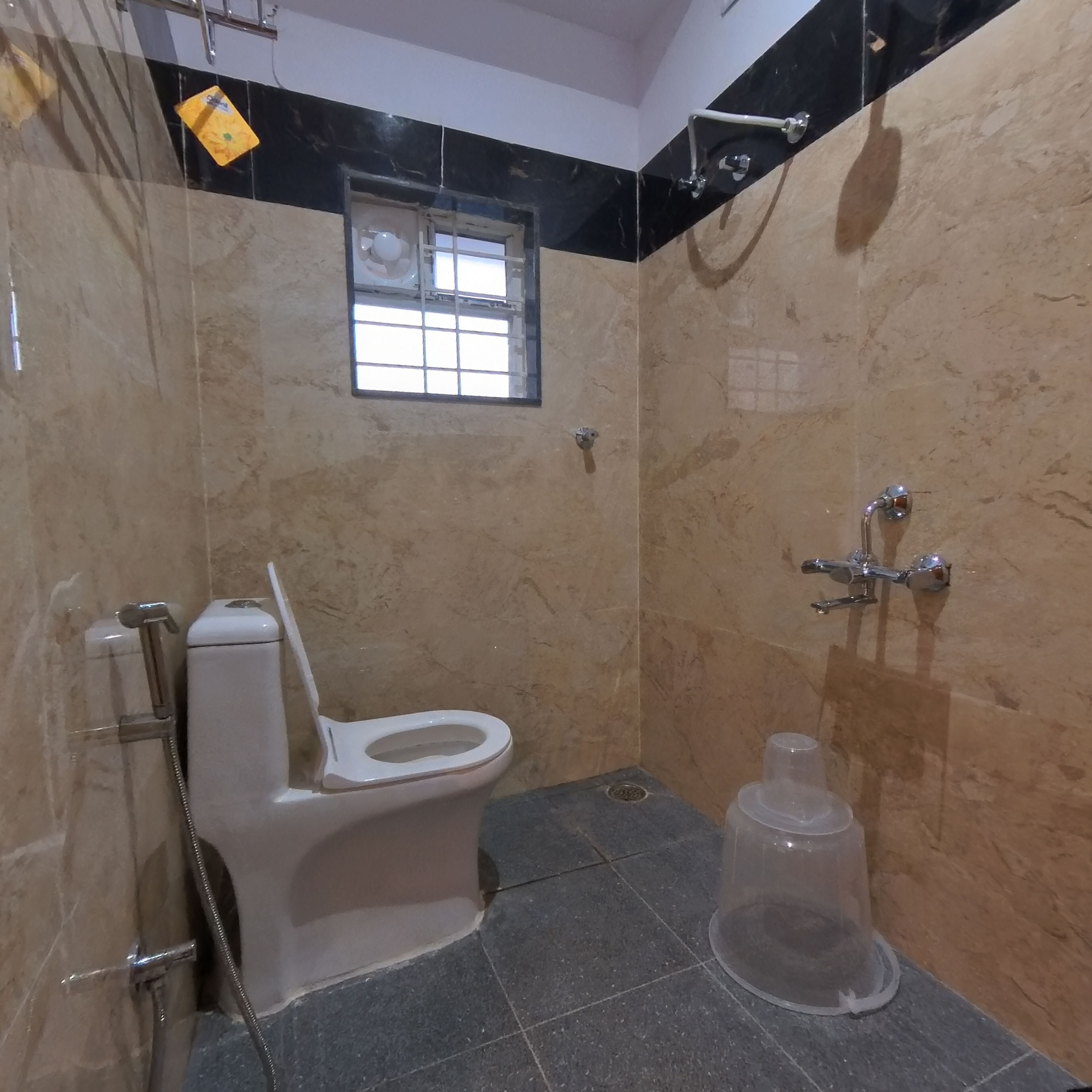 A bathroom with a toilet, shower, and a window.