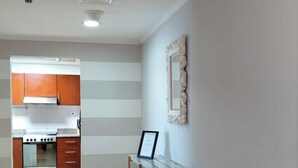 A modern kitchen with wooden cabinets, a stainless steel stove, and a built-in oven. There is a wooden table with shelves against the wall, and a framed picture hanging above it. - Charming and Comfortable 1BR | Jumeirah Bay X1| JLT (Dubai)