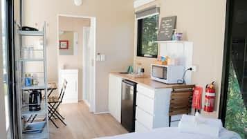 Habitació compacta amb cuineta, un llit, taula petita i una cadira.