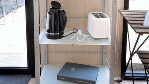 A shelf with glassware, a coffee maker, a toaster, and a laptop.