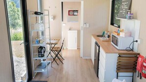 A compact kitchen with a microwave, a coffee maker, and a small dining area with a table and chairs.