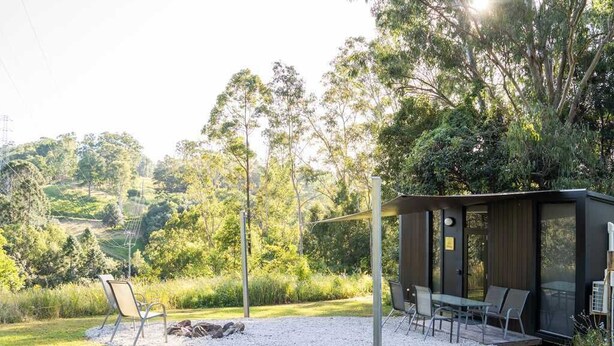 A modern outdoor seating area with a table and chairs, surrounded by a gravel path and greenery.