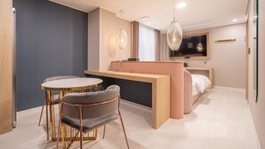 Een moderne hotelkamer met een eethoek, een bed en een kleine kitchenette.