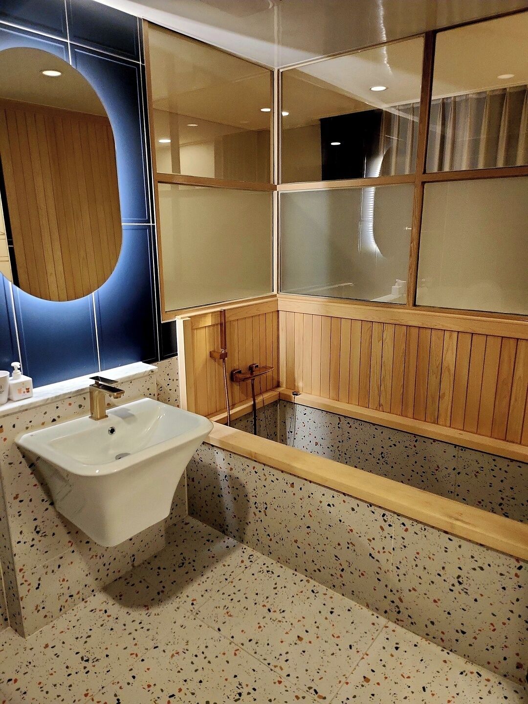 Ein modernes Badezimmer mit freistehender Waschtasche, Holzvertäfelung und einem großen Spiegel.
