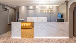 Een modern hotelontvangst met een marmeren balie, een receptie en een bordje voor Hotel Brown-Dot.