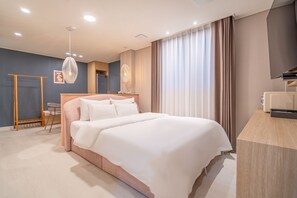 Une chambre d’hôtel moderne, dotée d’un grand lit, d’un bureau et d’une télévision.