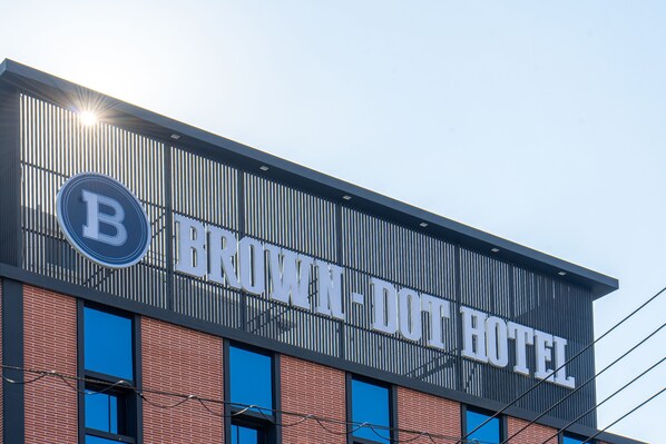 Une enseigne d’hôtel avec un grand logo en forme de « B » et le nom « BROWN DOT HOTEL ».