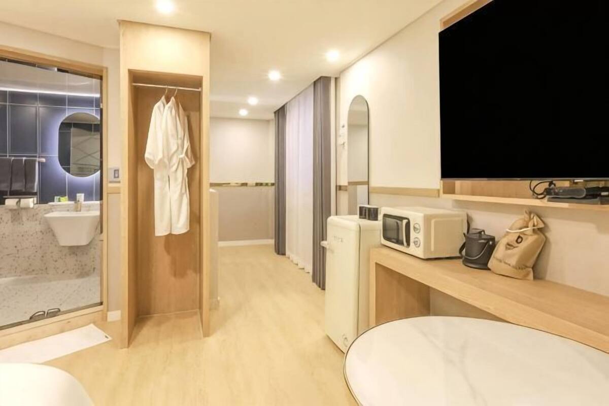Habitación de hotel con ducha, cama, televisión y microondas.