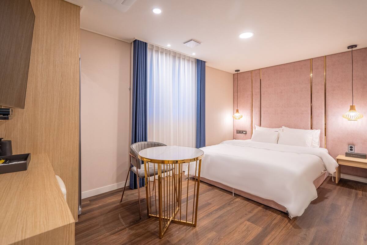 Una habitación de hotel moderna con una cama grande, una mesa redonda, un escritorio y una silla.