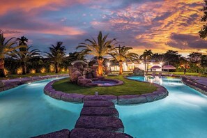 Relax by the serene pool surrounded by lush greenery and palm trees.