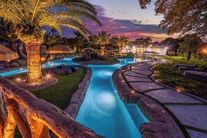 A pool area with a winding water feature, palm trees, and stone pathways. - One and Only Lazy River Pool Villa (Miami)